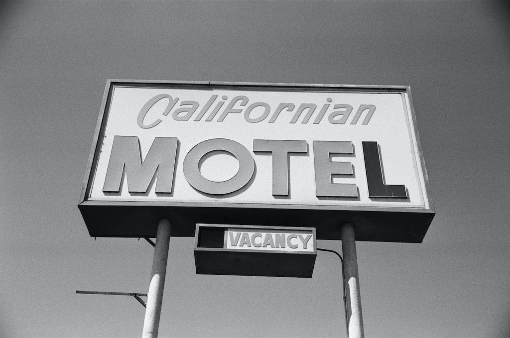 Black and white photo of sign reading "Californian Motel" with "Vacancy" underneath. Evolution of the Lodging Industry hotel motel inn hospitality