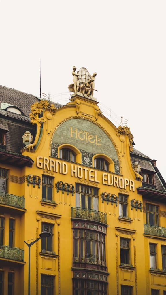 Front of the Grand Hotel europa Prague, a brown and yellow building. Evolution of the Lodging Industry hotel motel inn hospitality